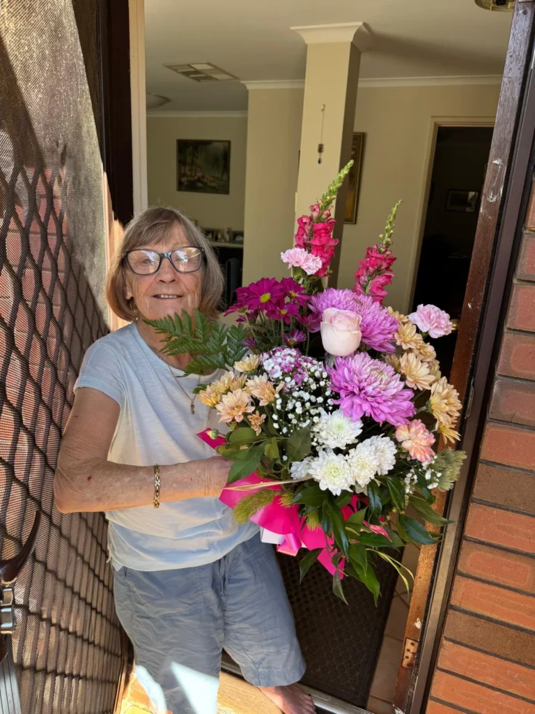 flower delivery aged care Perth elderly lady receiving fresh bouquet at home door: MS ROSE